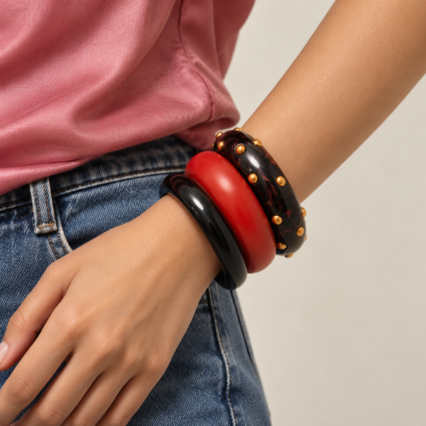 Chunky deep red resin bangles worn with a satin blouse and denim
