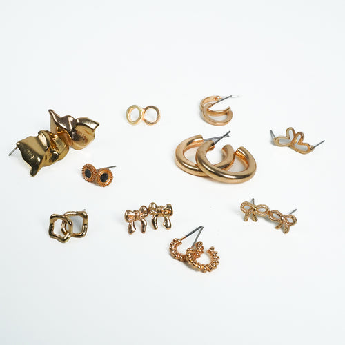Ten pairs of small gold-tone earrings laid out as a set