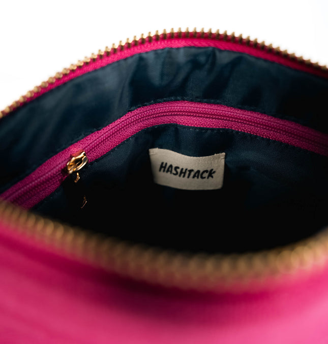 Side angle of fuchsia pink utility pouch highlighting secure gold-tone metal zipper and wristlet strap
