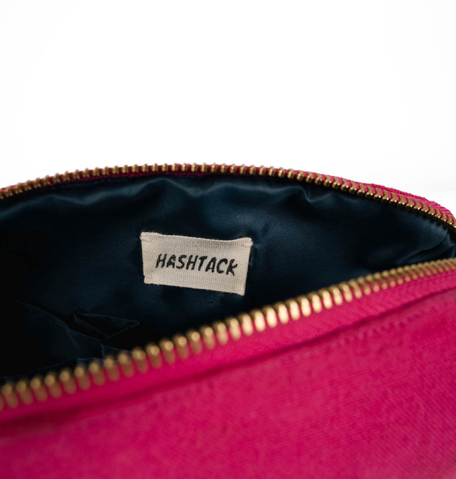 Side angle of blush pink utility pouch highlighting secure gold-tone metal zipper and wristlet strap