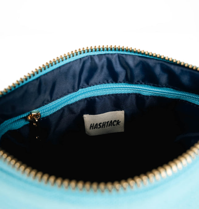 Side angle of lagoon blue utility pouch highlighting secure gold-tone metal zipper and wristlet strap