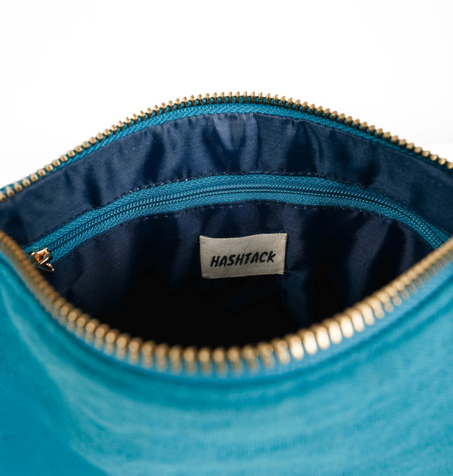 Side angle of turquoise blue utility pouch highlighting secure gold-tone metal zipper and wristlet strap