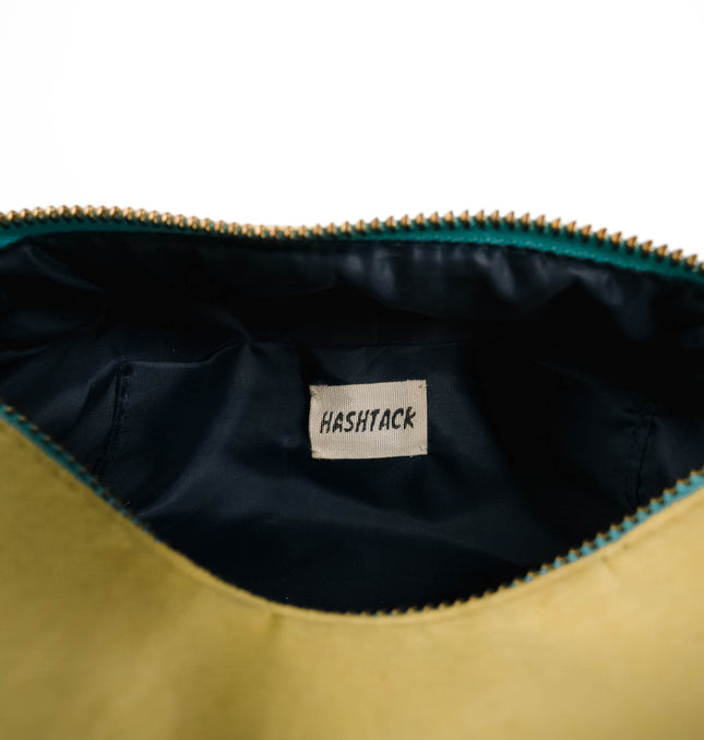 Side angle of yellow canvas utility pouch highlighting secure gold-tone metal zipper and wristlet strap