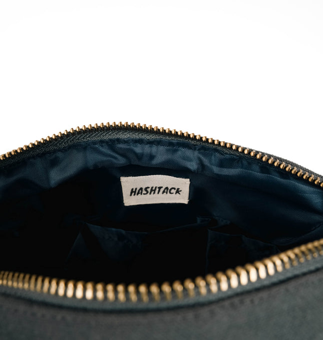 Side angle of charcoal black utility pouch highlighting secure gold-tone metal zipper and wristlet strap